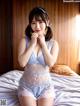 A woman in a blue lingerie sitting on a bed.