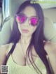 A woman wearing pink sunglasses sitting in a car.