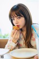 A woman sitting at a table eating a piece of food.