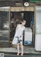 A woman standing in front of a store wearing a white dress.