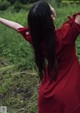 A woman in a red dress standing in a field.