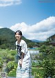 A woman standing in front of a lush green field.