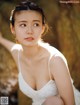 A woman in a white dress sitting on a rock.