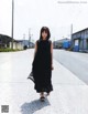 A woman in a black dress walking down a street.