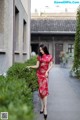 A woman in a red dress is walking down a sidewalk.